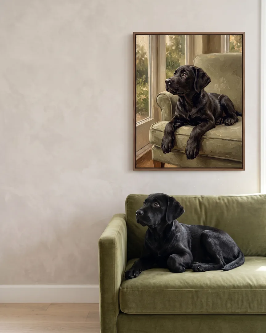 Bear, un chiot labrador noir, à côté d'une toile encadrée brune de son portrait Lumière du matin.