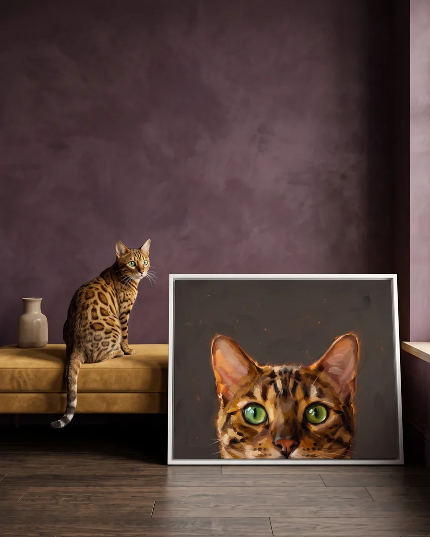 Jasper, a Bengal, beside a white framed canvas of their own Painted Peek portrait.