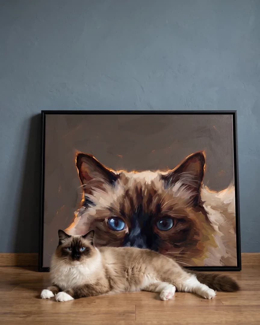 Willow, a Ragdoll, beside a black framed canvas of their own Painted Peek portrait.