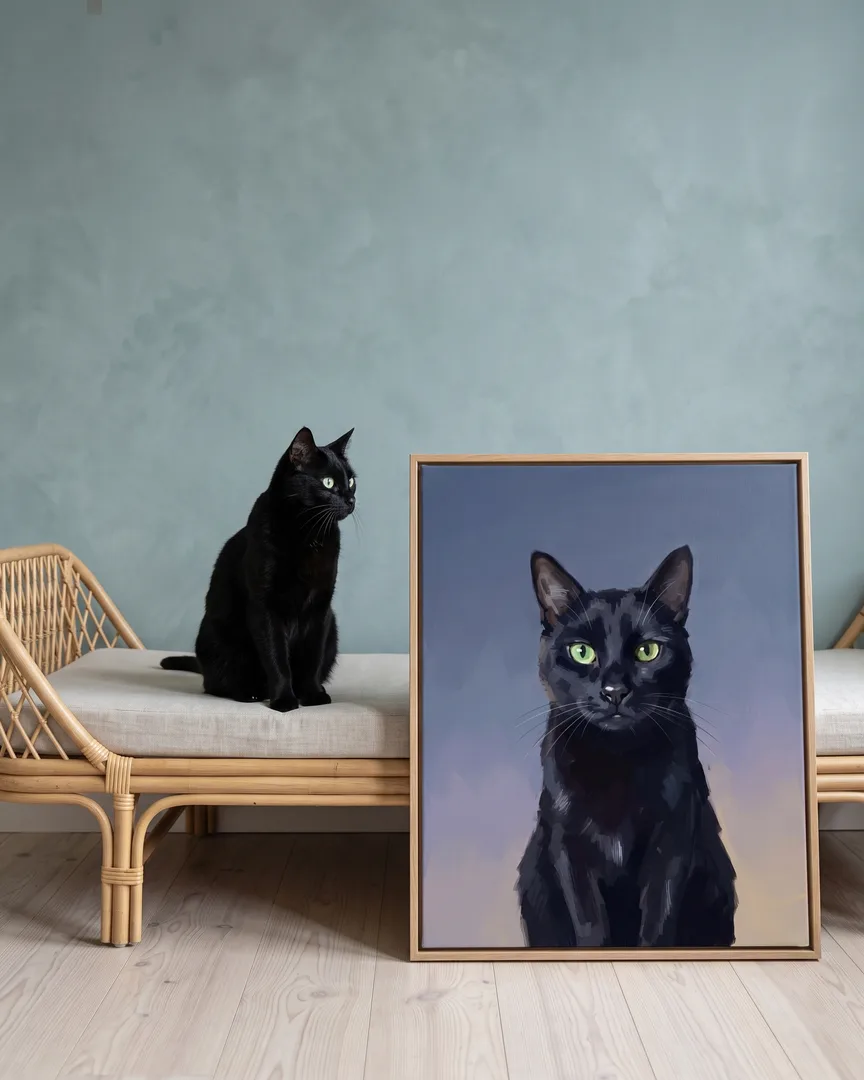 Ombre, un chat noir, à côté d'une toile encadrée en chêne naturel de son portrait Portrait ardoise.