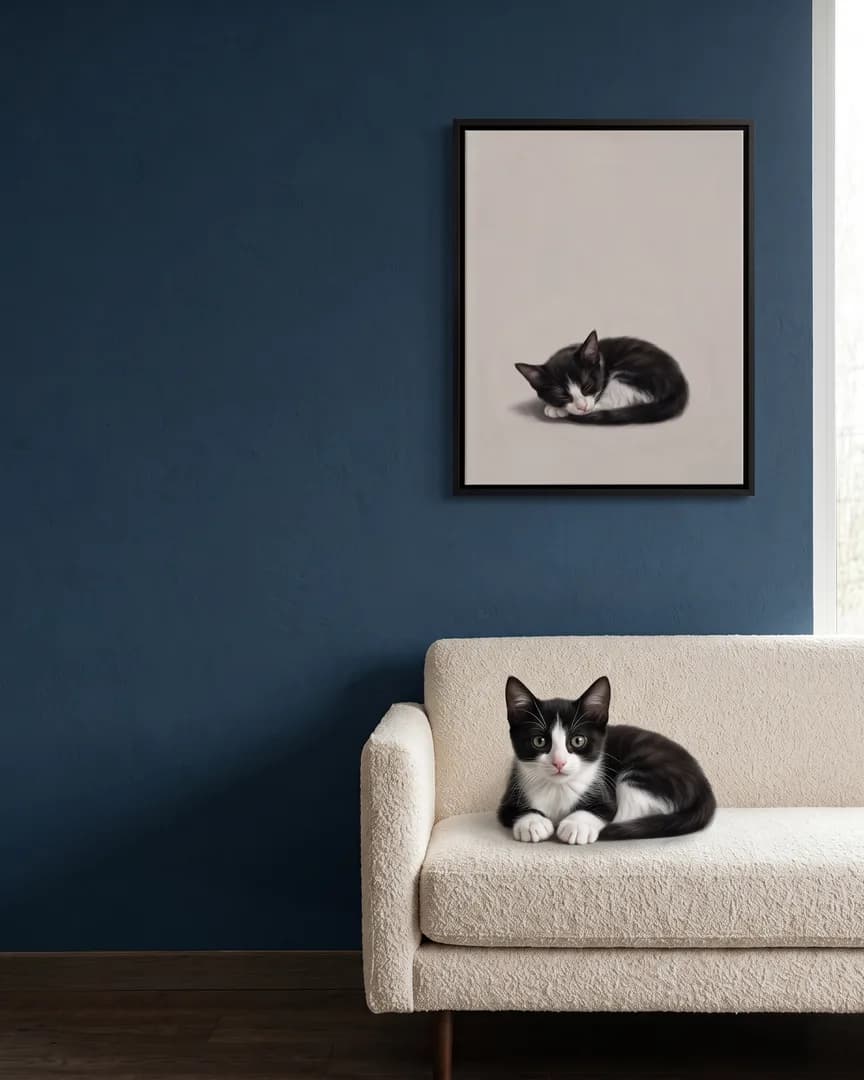 Oreo, a tuxedo domestic shorthair kitten, beside a black framed canvas of their own Soft Hush portrait.