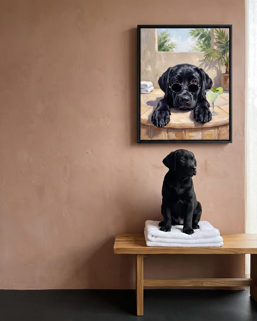 Bear, a black Labrador retriever puppy, beside a black framed canvas of their own Tub Edge Shades portrait.