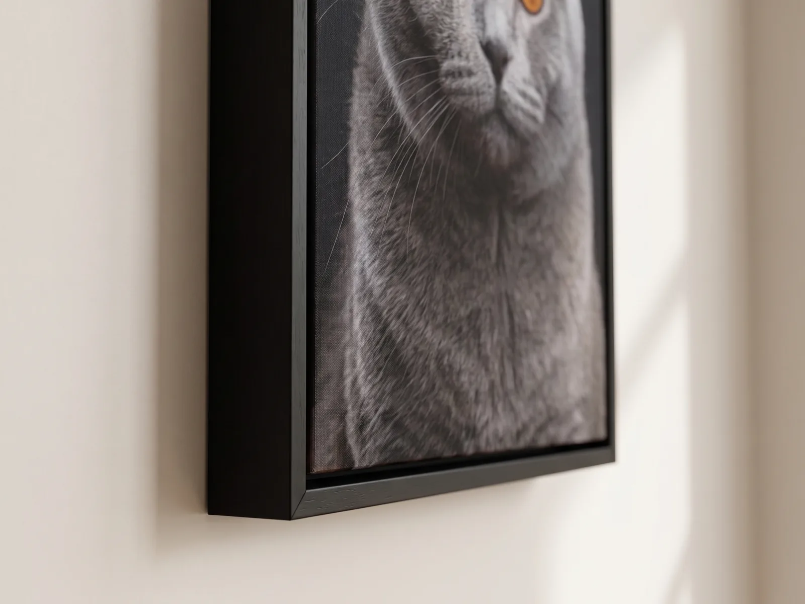 The lower corner of a black float frame on a wall, seen from the side, with a slim front face, a deep side and a narrow gap around the canvas edge
